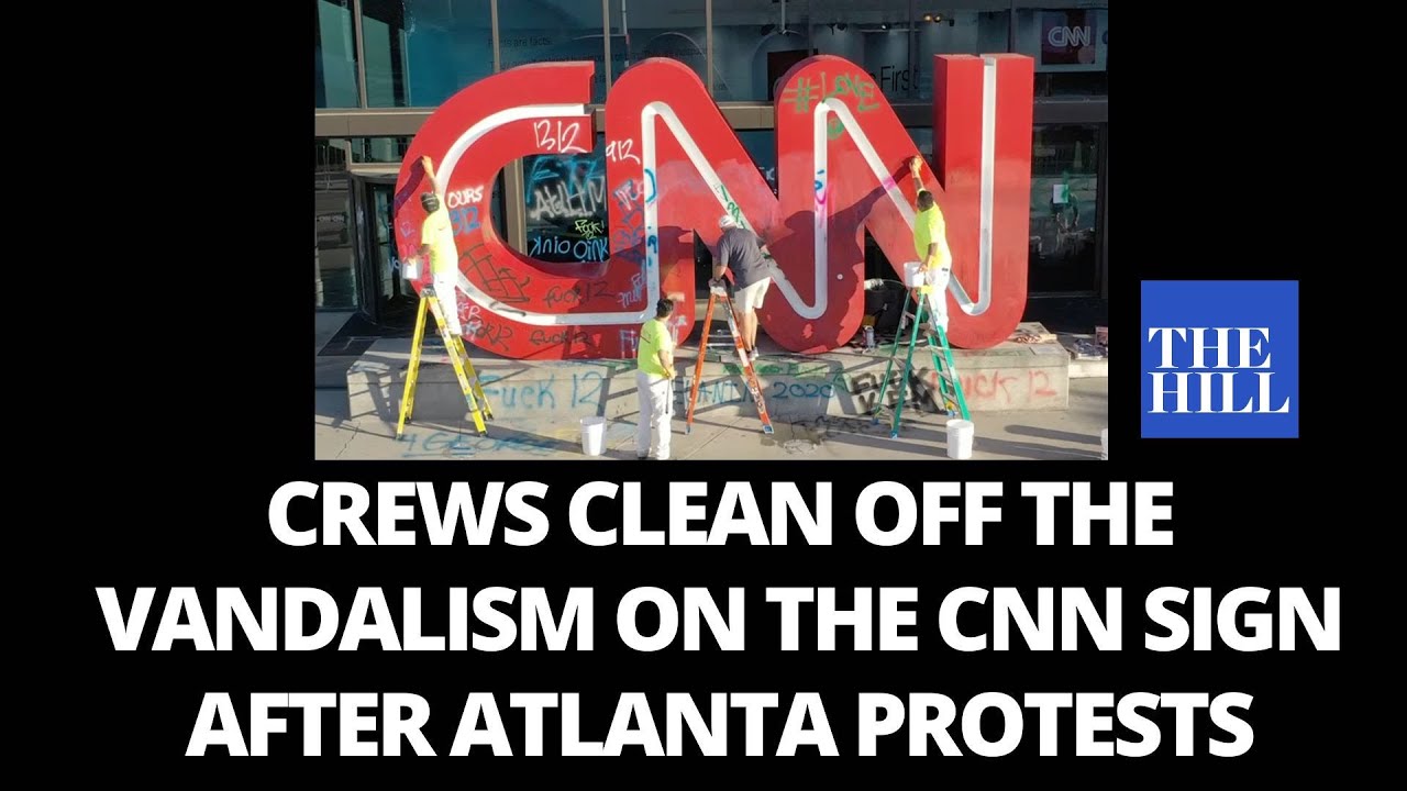 Crews clean off the vandalism on the CNN sign after Atlanta protests
