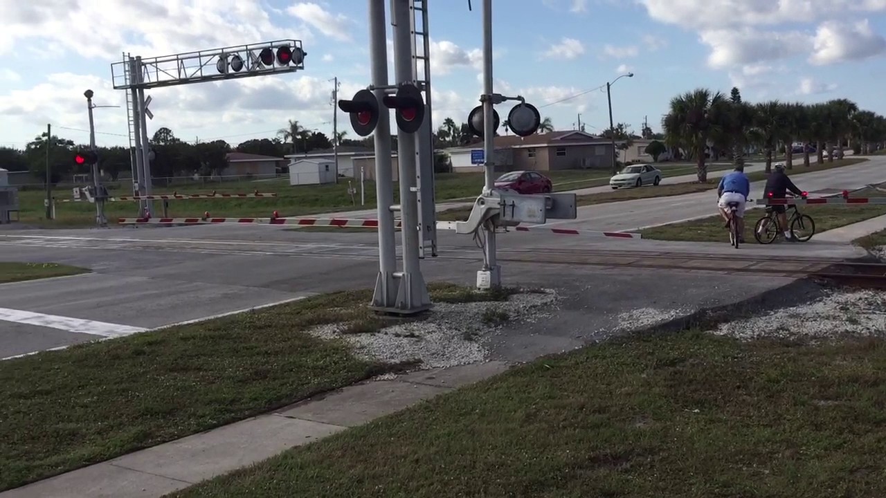 FEC TRAIN 920#2882@9:48am w/two people on bicycles going around the gates!