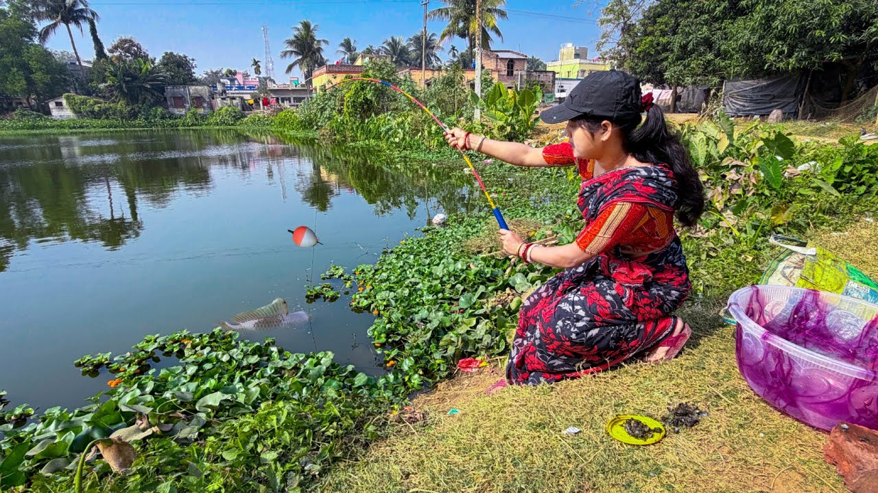 A cute girl is catching fish with a fishing rod using bait she collected from nature