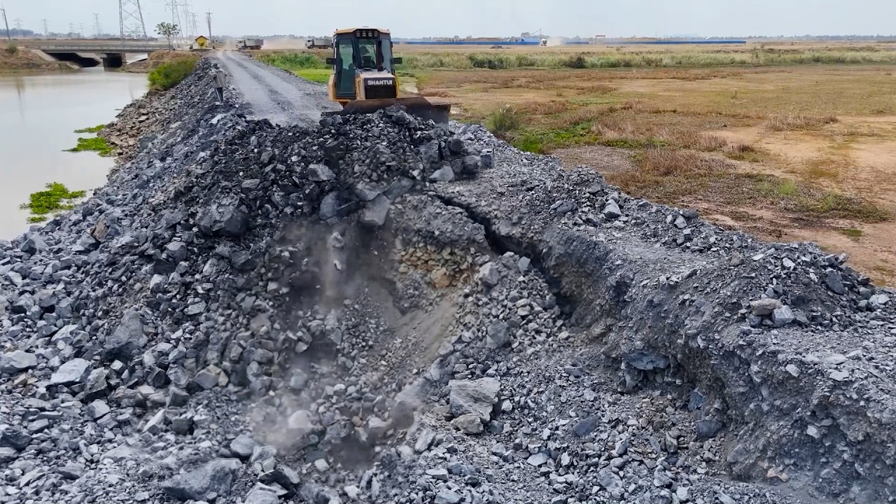 replenishing stone on damaged road surfaces, bulldozer push stone and dump truck transport the stone