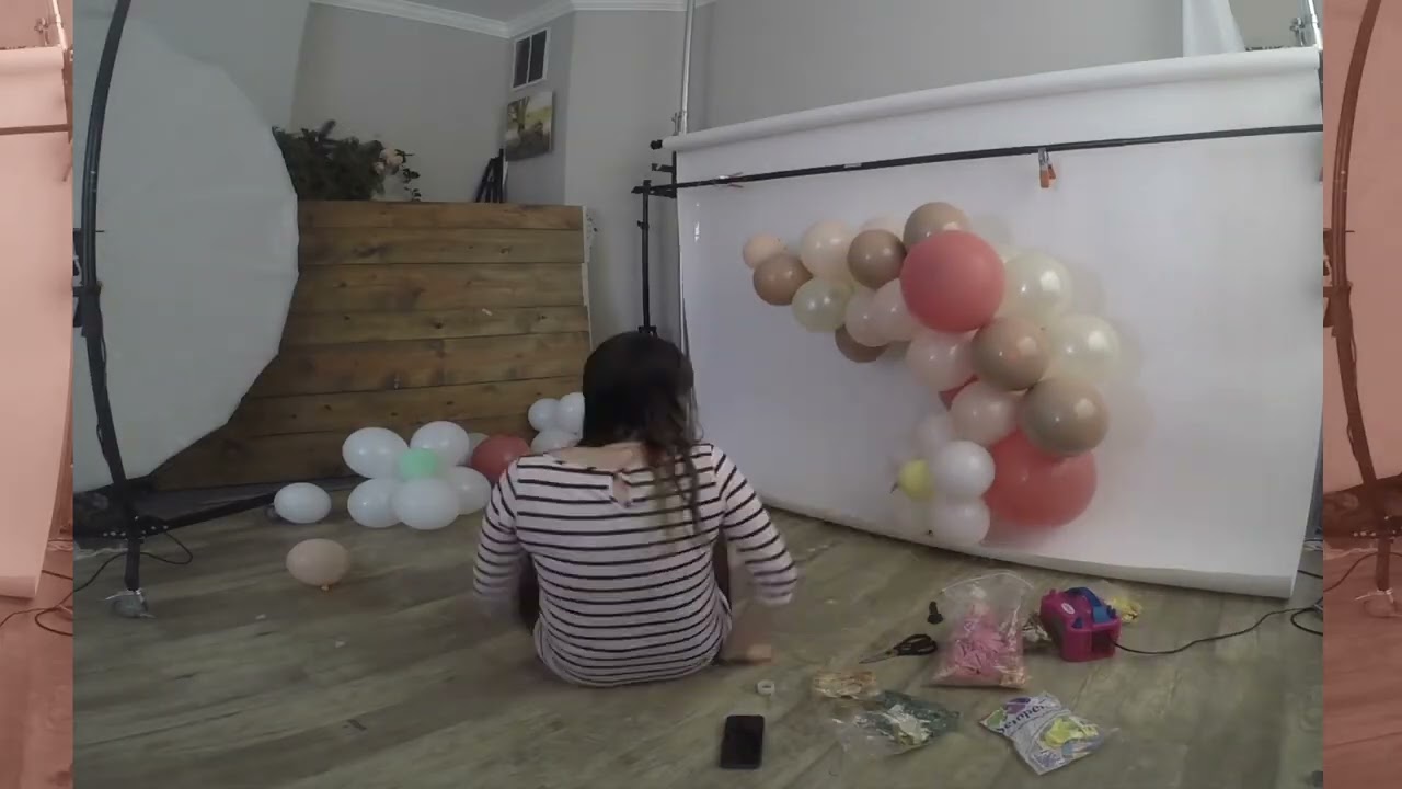 Build a balloon arch with daisies for 1st birthday cake smash session in photography studio