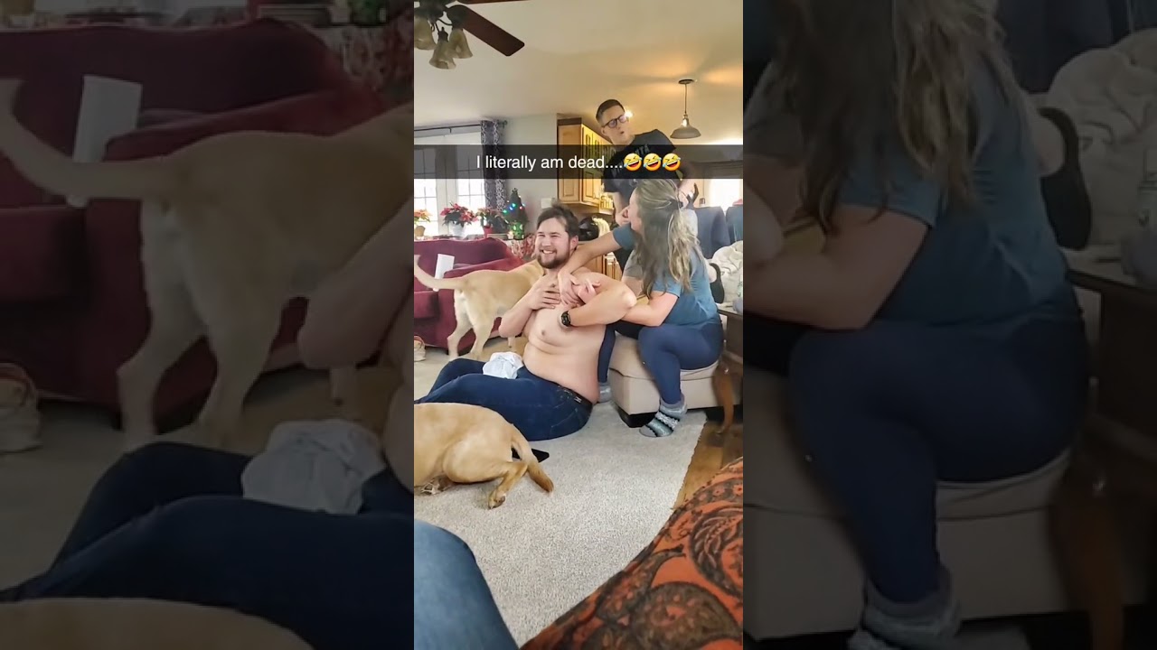 Guy is surprised by dog licking his chest while his sister is trying to help him stretch!
