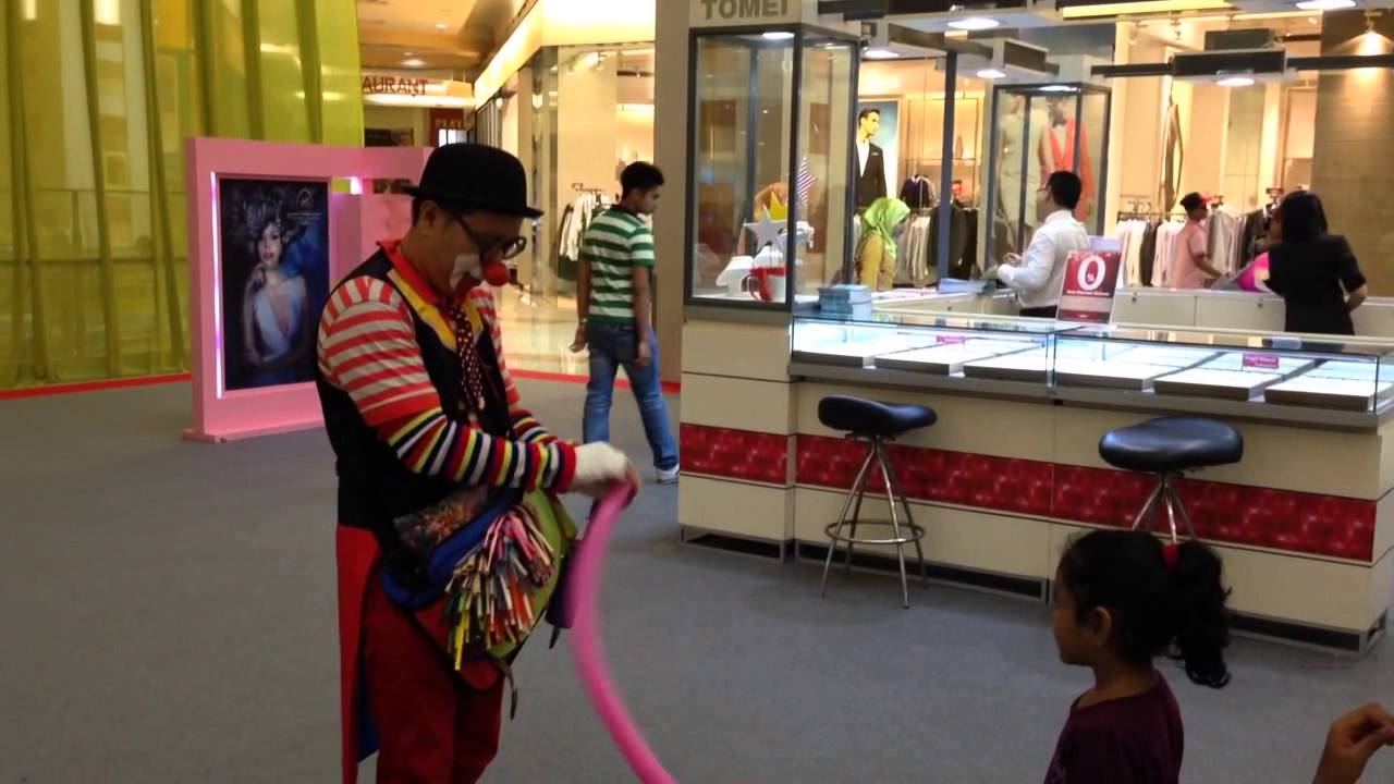 Clown shocked after blowing a balloon burst while the girls laugh