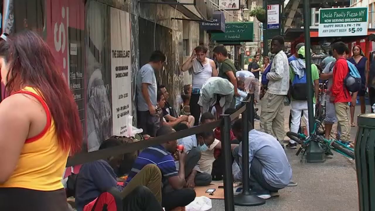 Dozens of migrants camp outside Roosevelt Hotel; sign says hotel at capacity