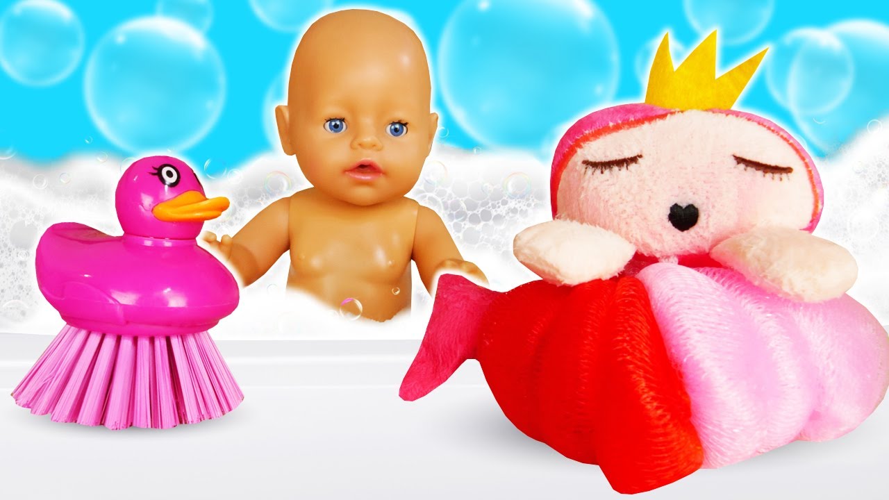 Кукла-младенец принимает ванну в игрушечной ванночке с разноцветной пеной и одевается.