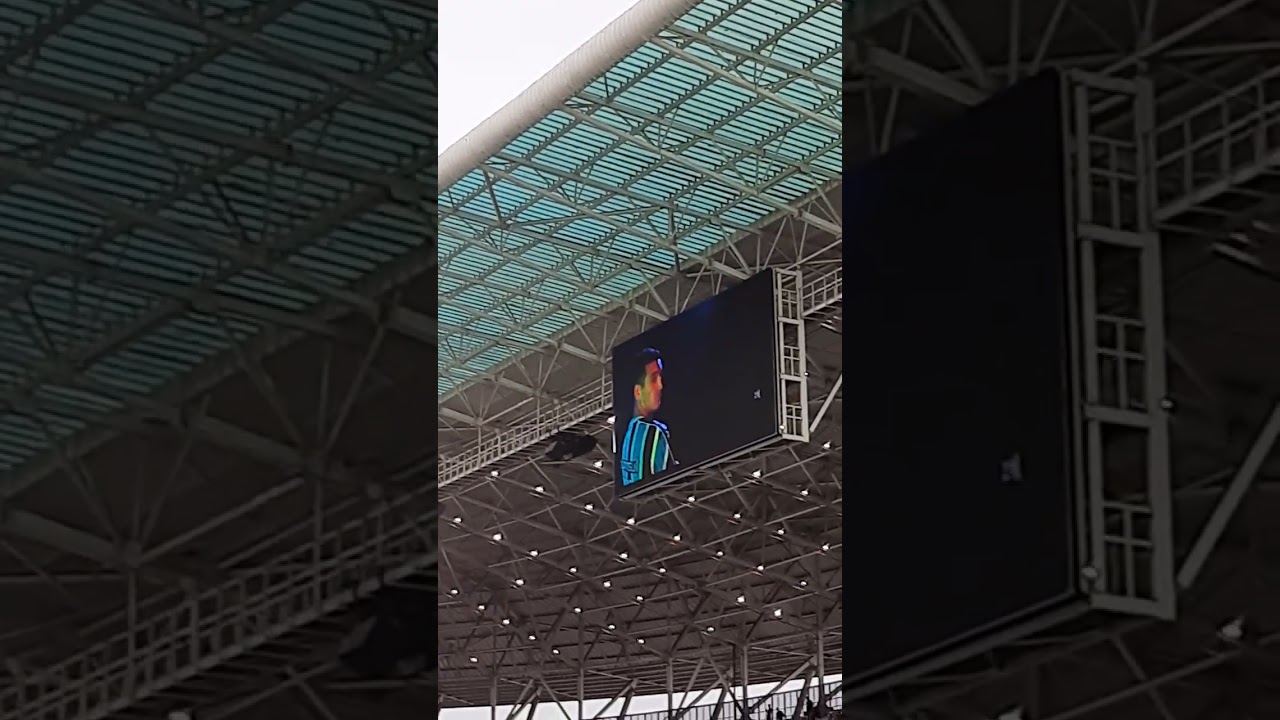 Escalação do Grêmio nos alto-falantes da Arena e filmagem da torcida do Corinthians.
