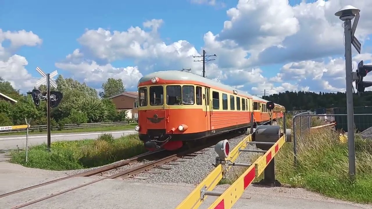 rälsbuss YBo5p ( och släpvagnar) passerar järnvägsövergång i Gunsta