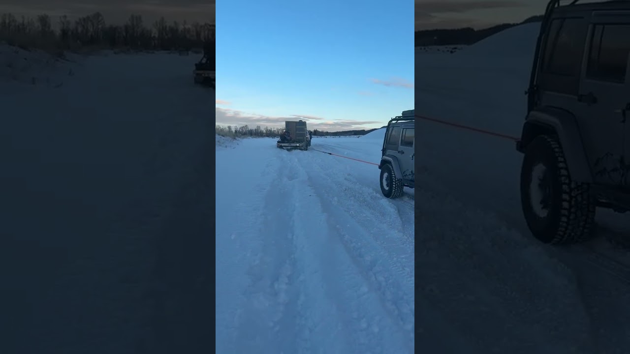 Jeep rescuing Chevy and trailer from snow drift 