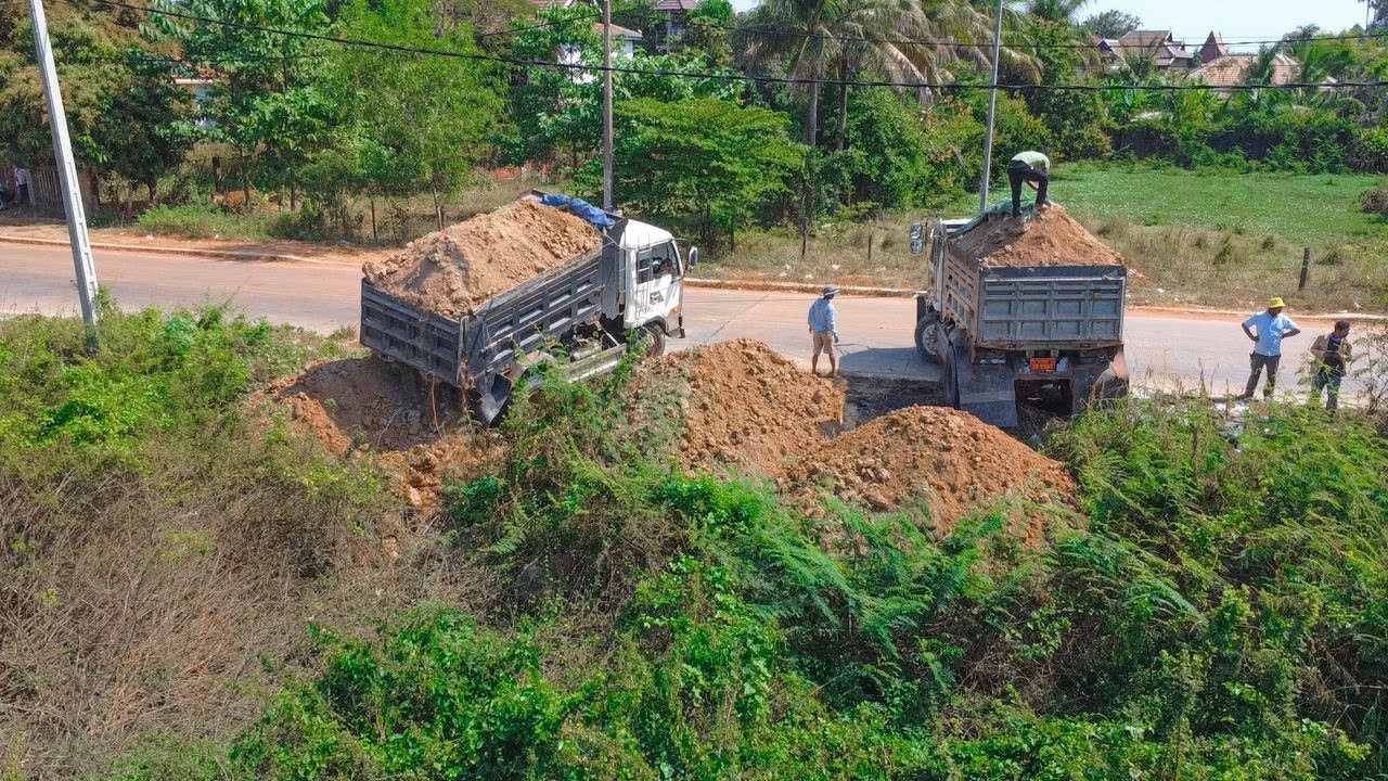 New landfill cleaning forest by Komatsu dozer pushing soil with Nissan trucks 