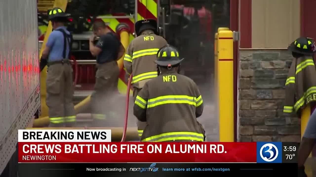 Firefighters work to put out several vehicles on fire at Newington business