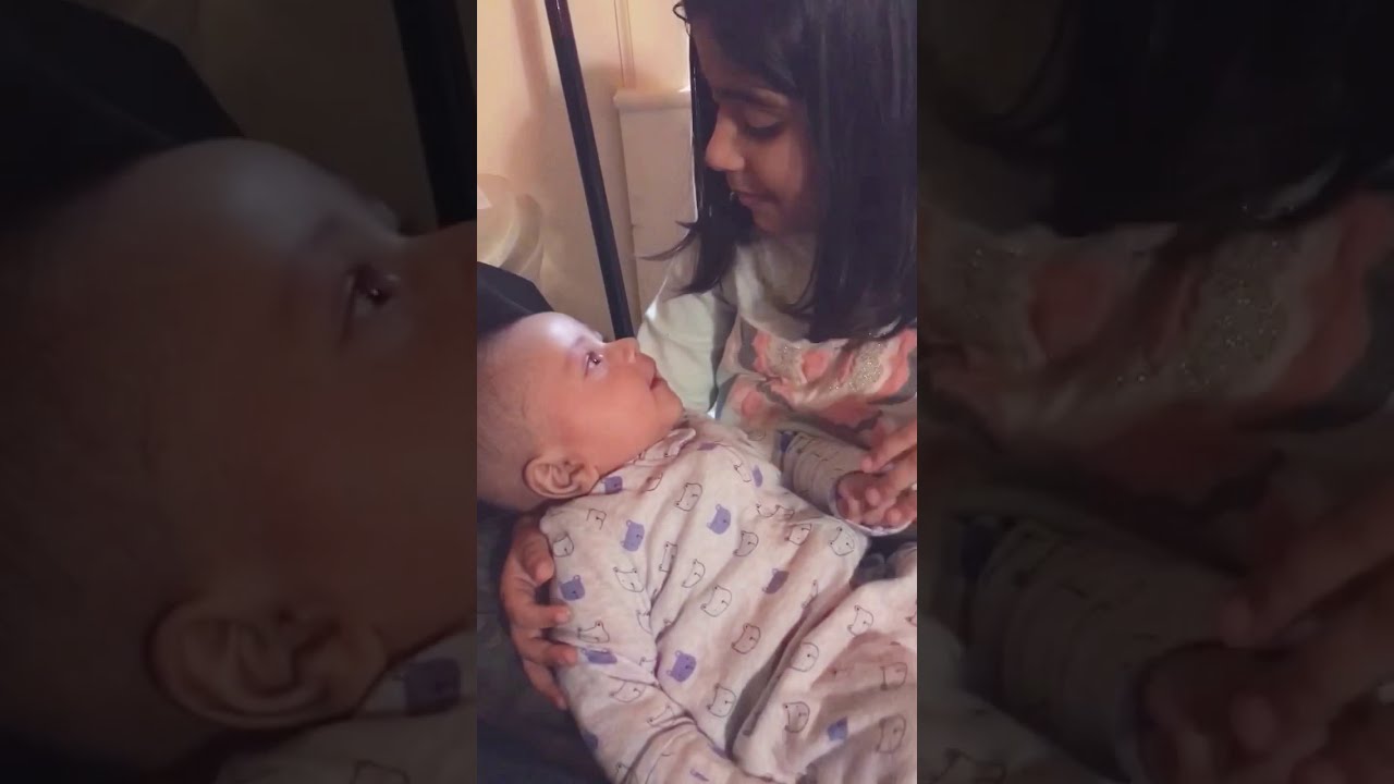 Big sister talking to baby brother. Super cute sibling moment.