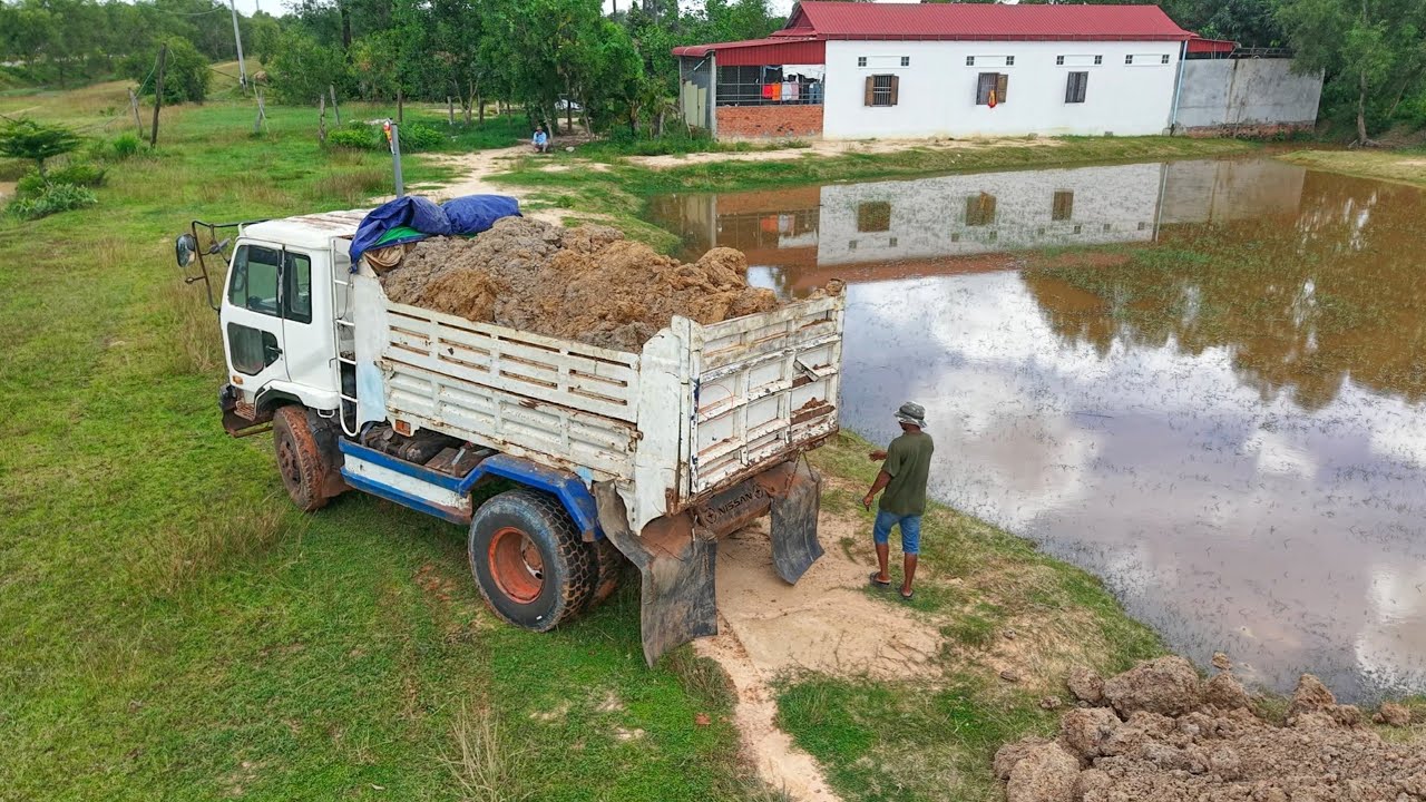 Many dump truck dumping soil with small bulldozer pushing soil cleaning water 