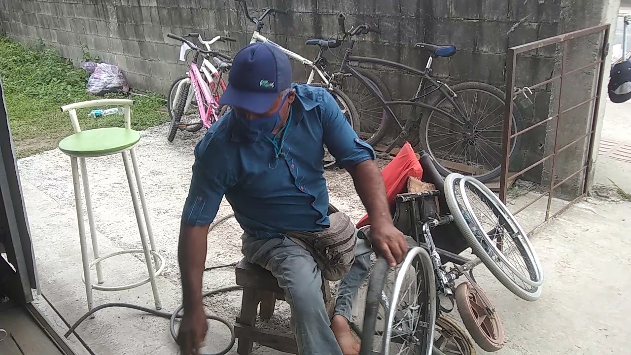 Cadeirante Edivaldo trocando o pneu da sua cadeira de rodas.
