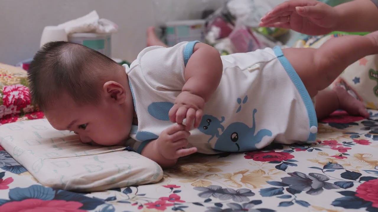 The baby is learning to roll over. Em Bé tập lật người