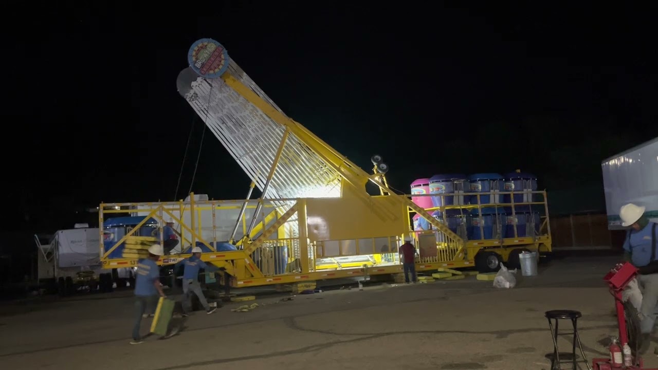 Rifle, CO fairgrounds, carnival packs up amusement park rides onto trucks folding Ferris Wheel.