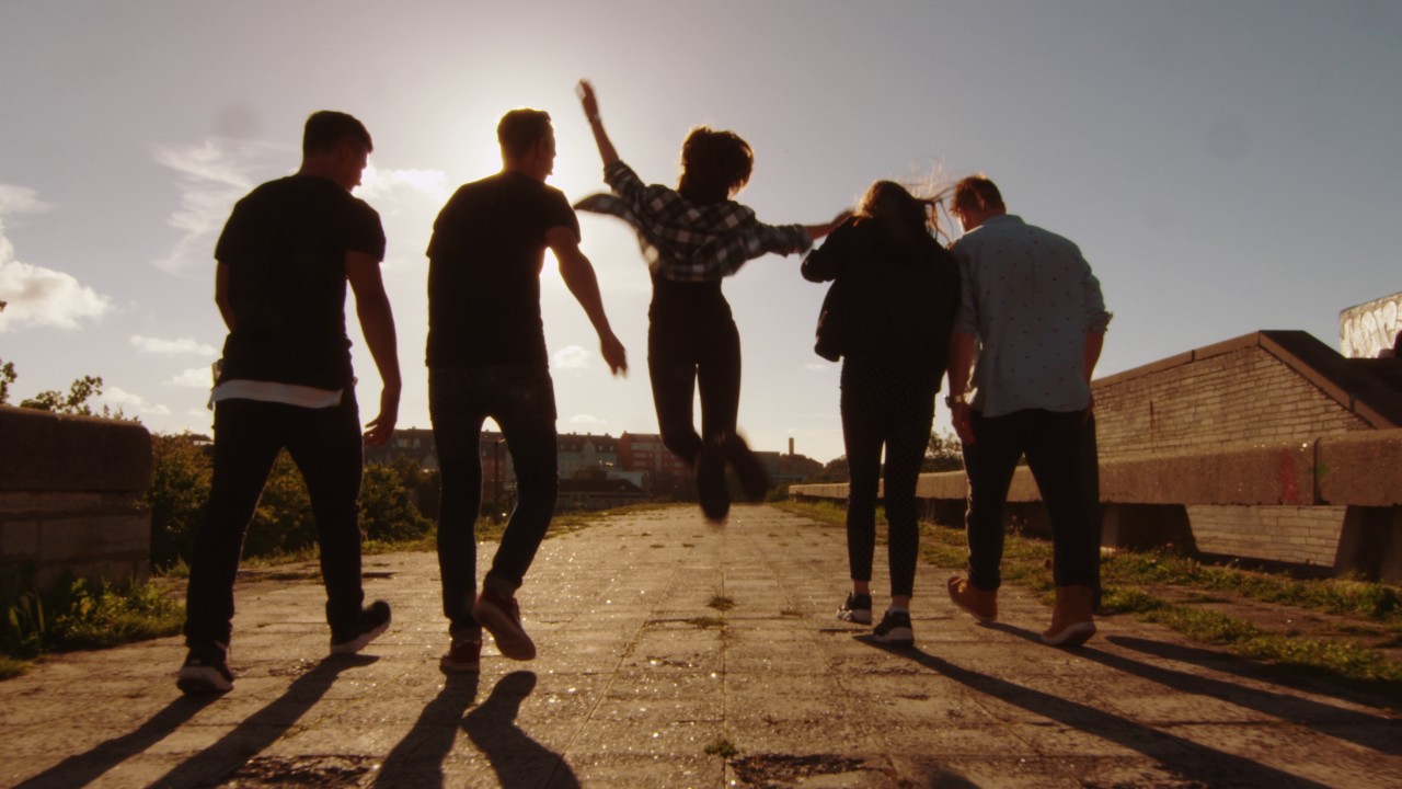 happy young people laughing and raising hands