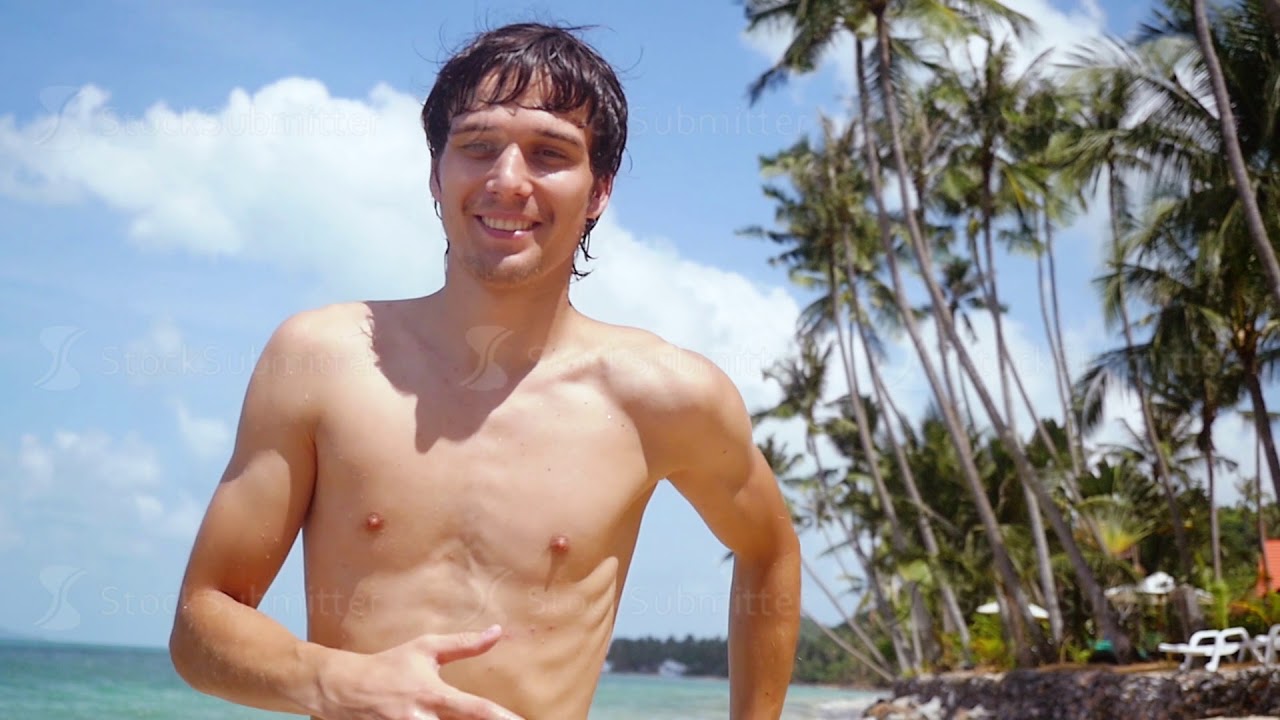 Young handsome man running on the beach at sunny day in slow motion. 1920x1080