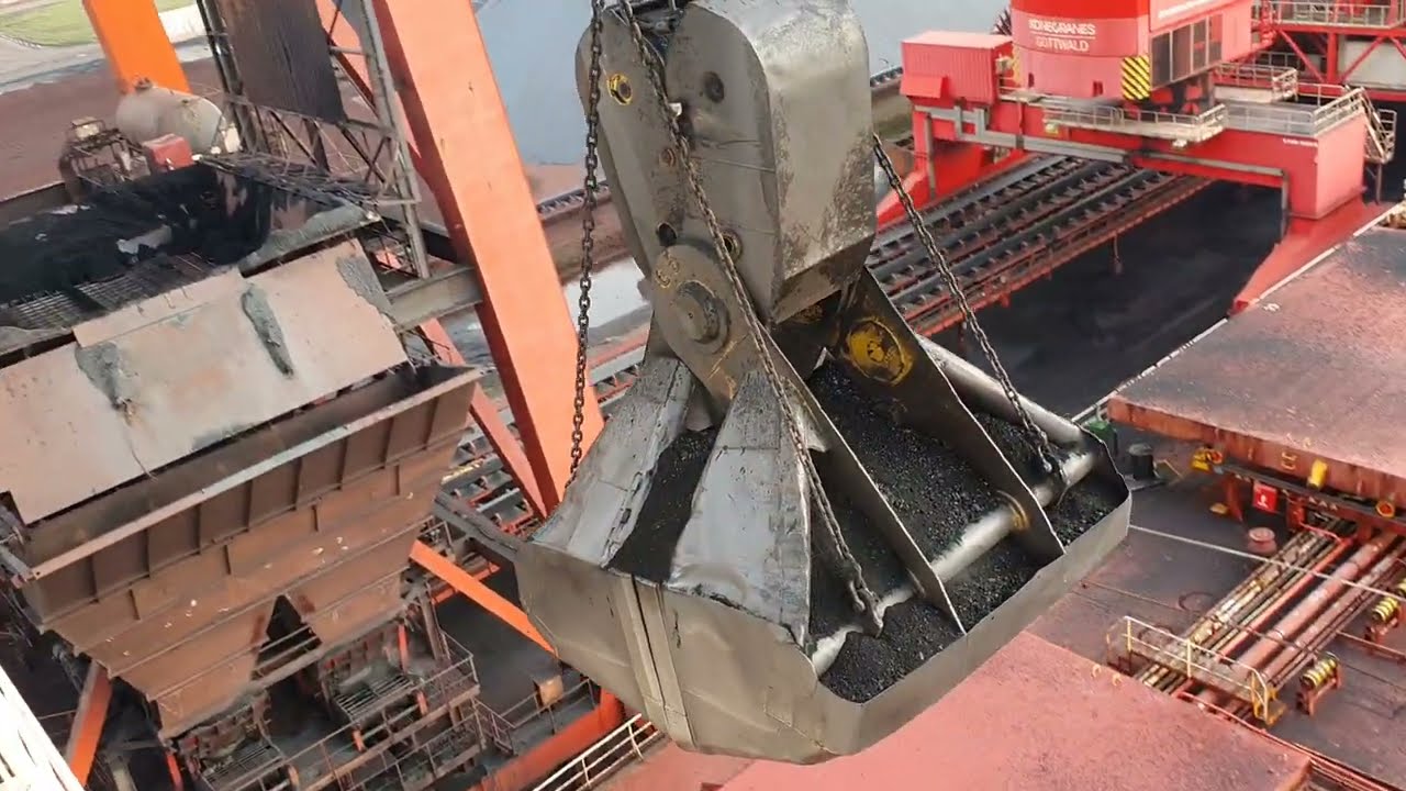 Unloading a 300 meter coal bulk ship. Bucket crane with massive bucket close to the wheelhouse