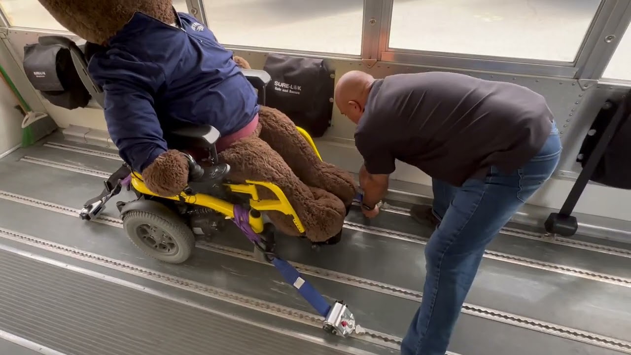 Securing a motorized or electric wheelchair to the school bus using the blue straps