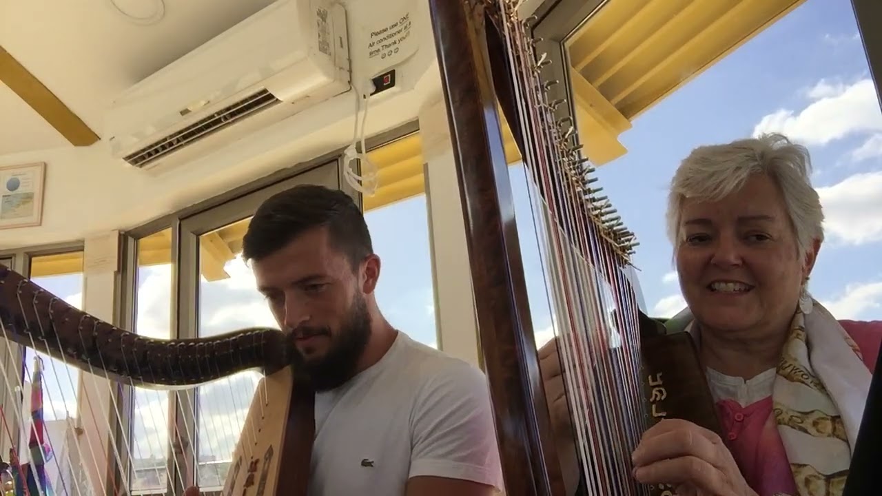 Peggy Powers singing and playing harp with friend