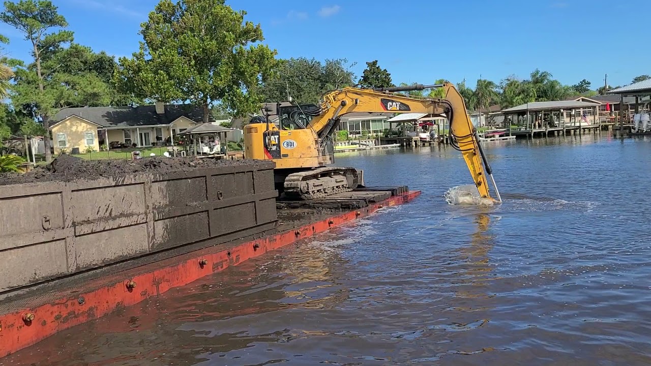 Excavator on barge dredging canal