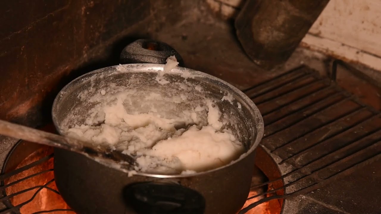 How we cook in Uganda village style. Cooking Posho with Groundnut paste on firewood and char coal