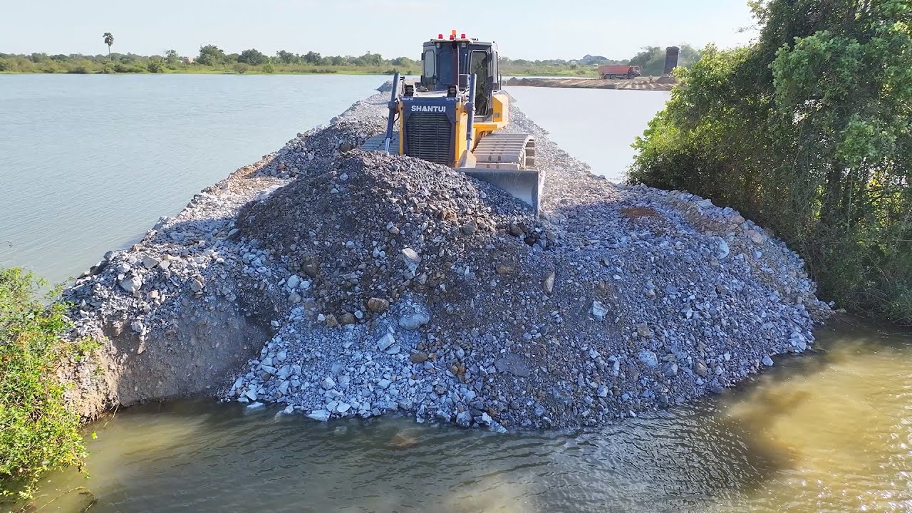 Unbelievable!! A project to pour large rocks around the lake to fill it with sand using bulldozers