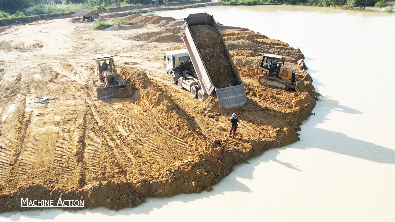 Best Operation Bulldozer Spreading Dirt Into Water And Dump Truck Moving Soil