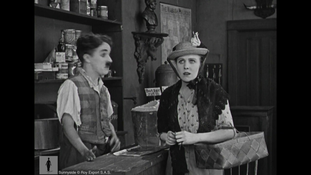 Charlie Chaplin, store clerk, helps forgetful customer (Edna Purviance)