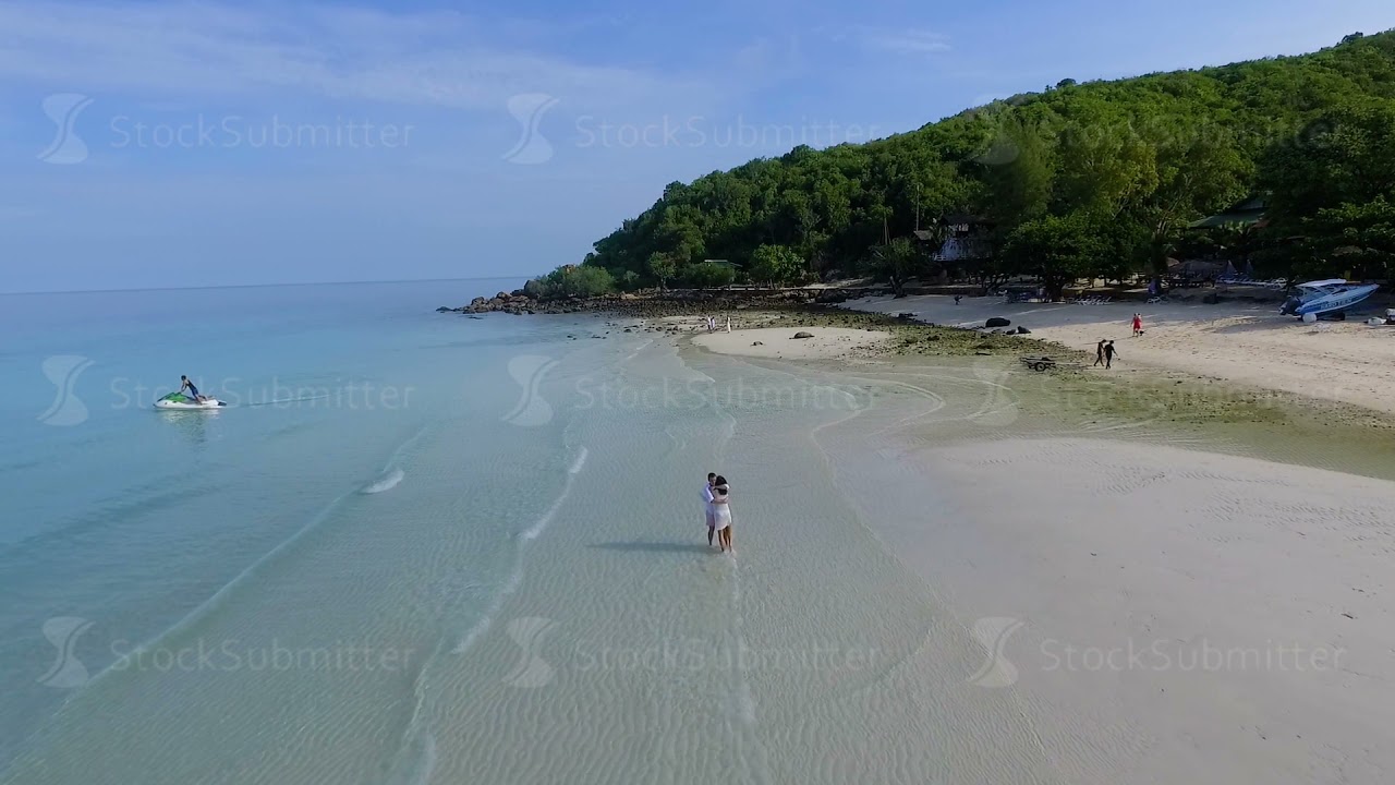 Couple walking on beach. Young happy interracial couple walking on beach smiling holding around each