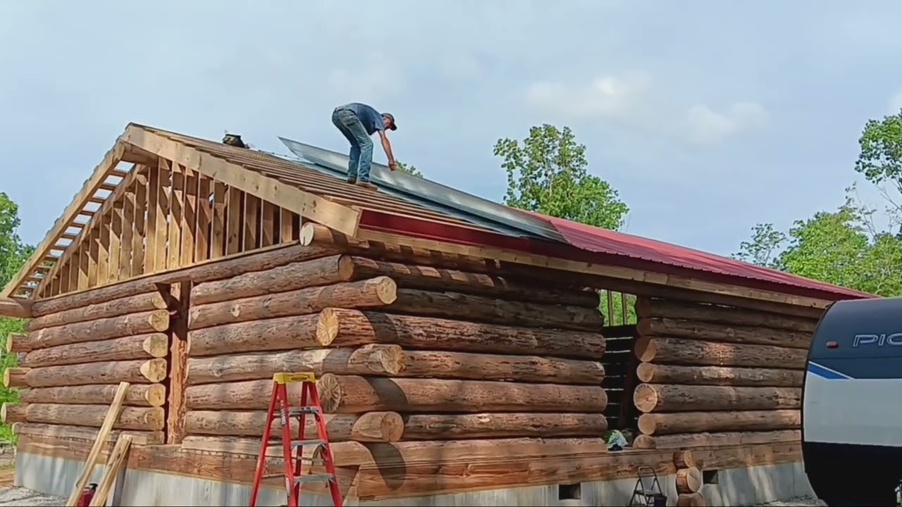 One man log cabin build. Roofing the cabin in barn red.