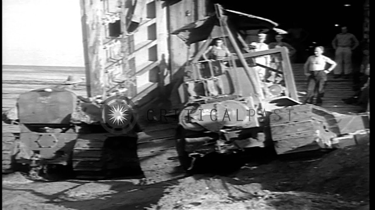 Soldiers watch as bulldozers are unloaded from a Landing Ship Tank at a beach in ...HD Stock Footage