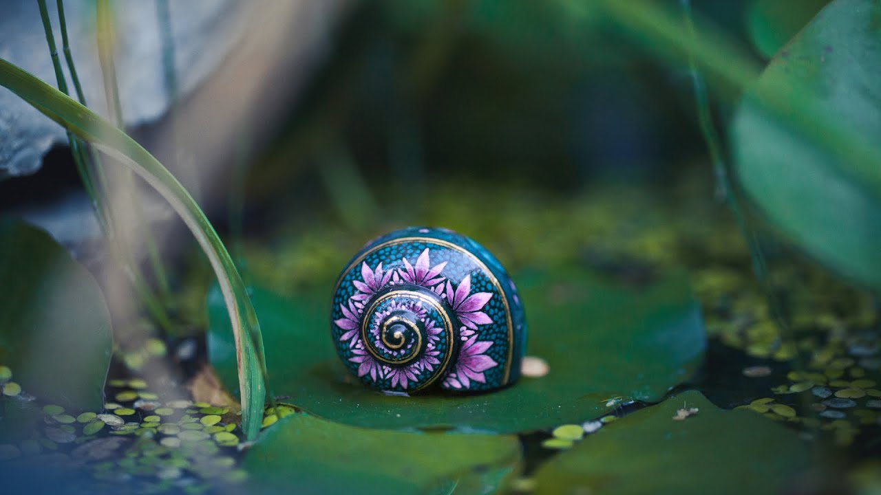 Painting a pink water lily on a tiny snail shell