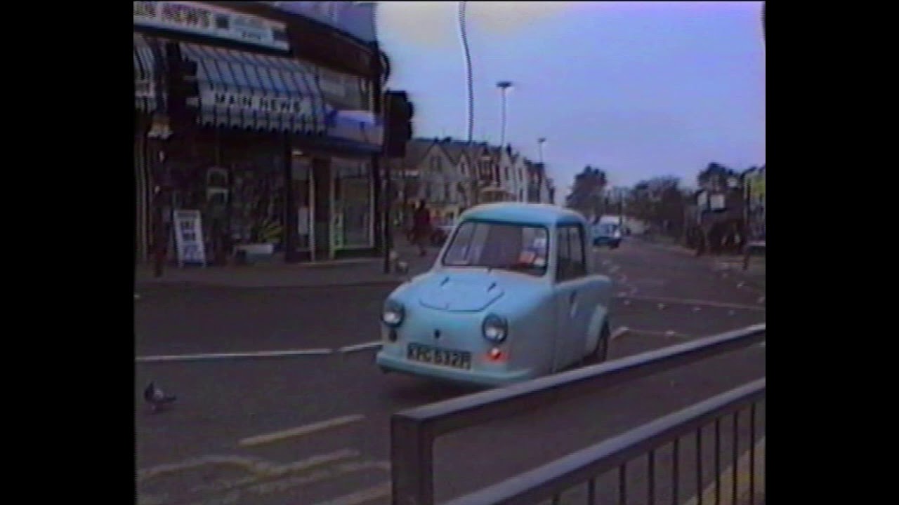 Lady in Invacar stops to let pigeon cross the street in Bournemouth, 1991