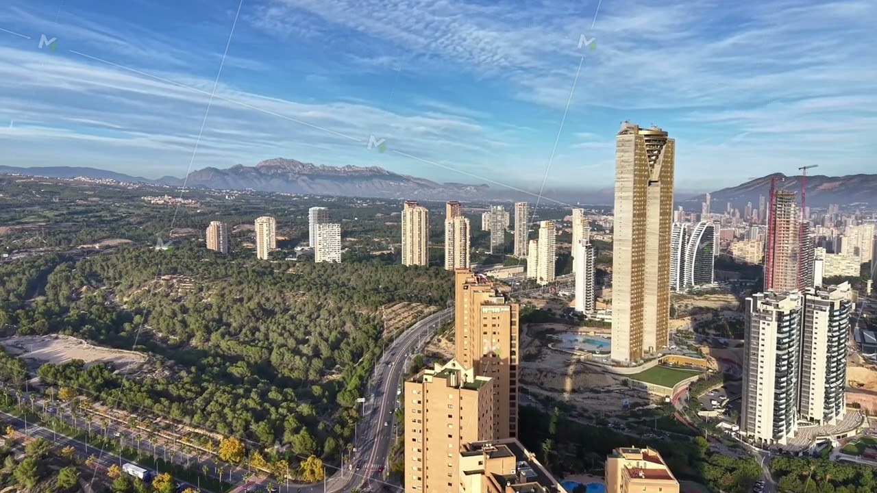 Aerial Daytime Panorama Capturing Luminous Architecture Amid Lush Valley And Mountain Range