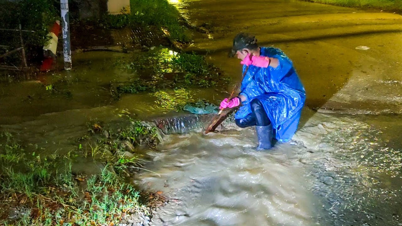 Checking Culvert On Street At Night While Raining