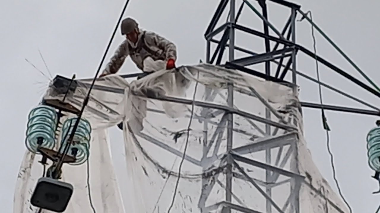 Ligne haute tension remise en peinture d'un pylône sous protection en zone urbaine.