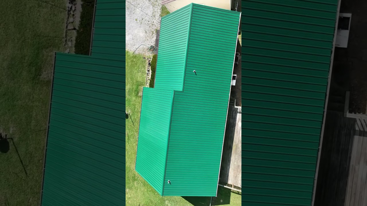 Spruce-green classic panel metal roof caps the Tennessee cottage with the surrounding treeline