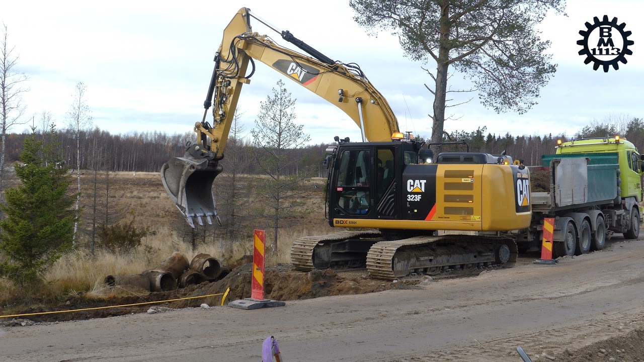 CAT 323F and gravel trucks in a roadwork