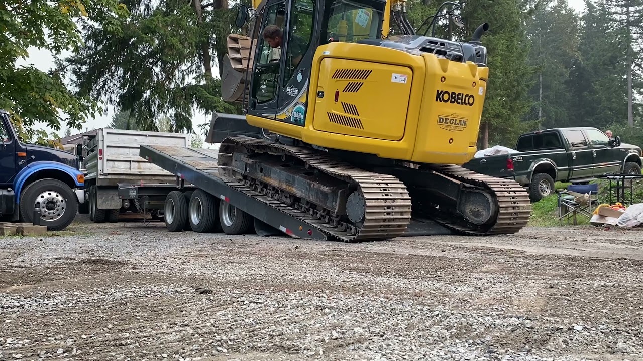 Loading Kobelco excavator on tilt deck tridem trailer.