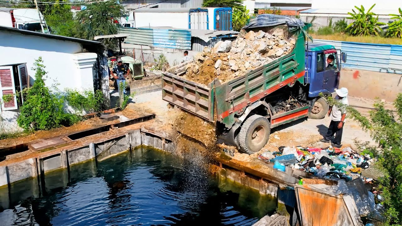 The deep flood land delete by big stone dump truck unload and bulldozer push for filling land