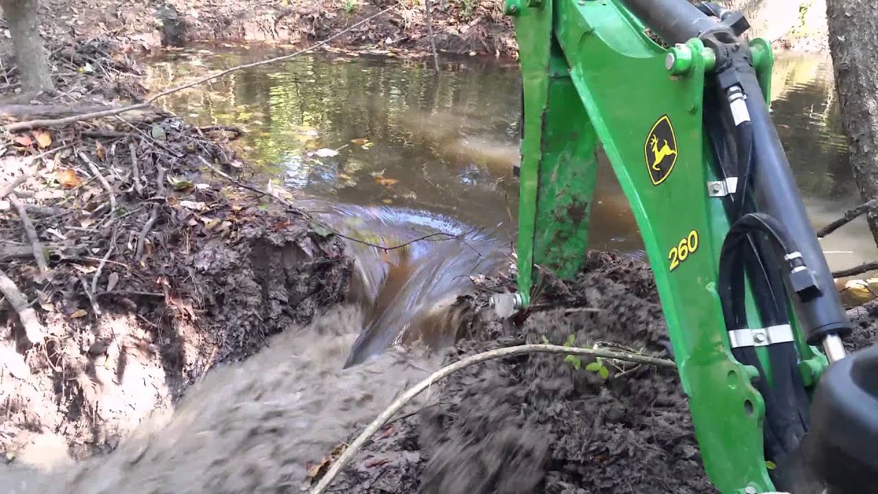 John Deere 1025r digging out a beaver dam