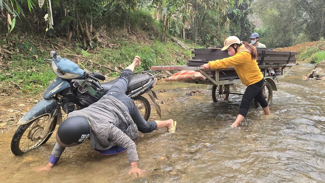 A rudimentary cart carrying doors crosses the middle of the stream.
