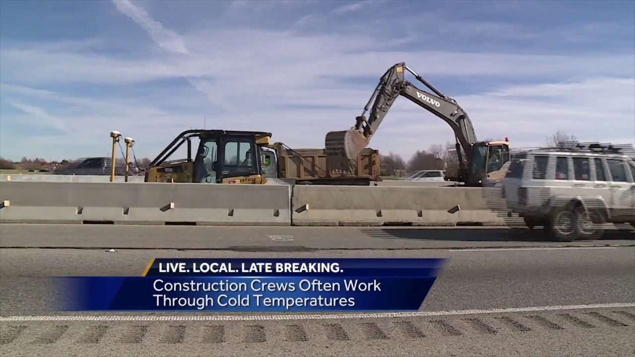 Construction workers try to keep warm as freezing weather moves in
