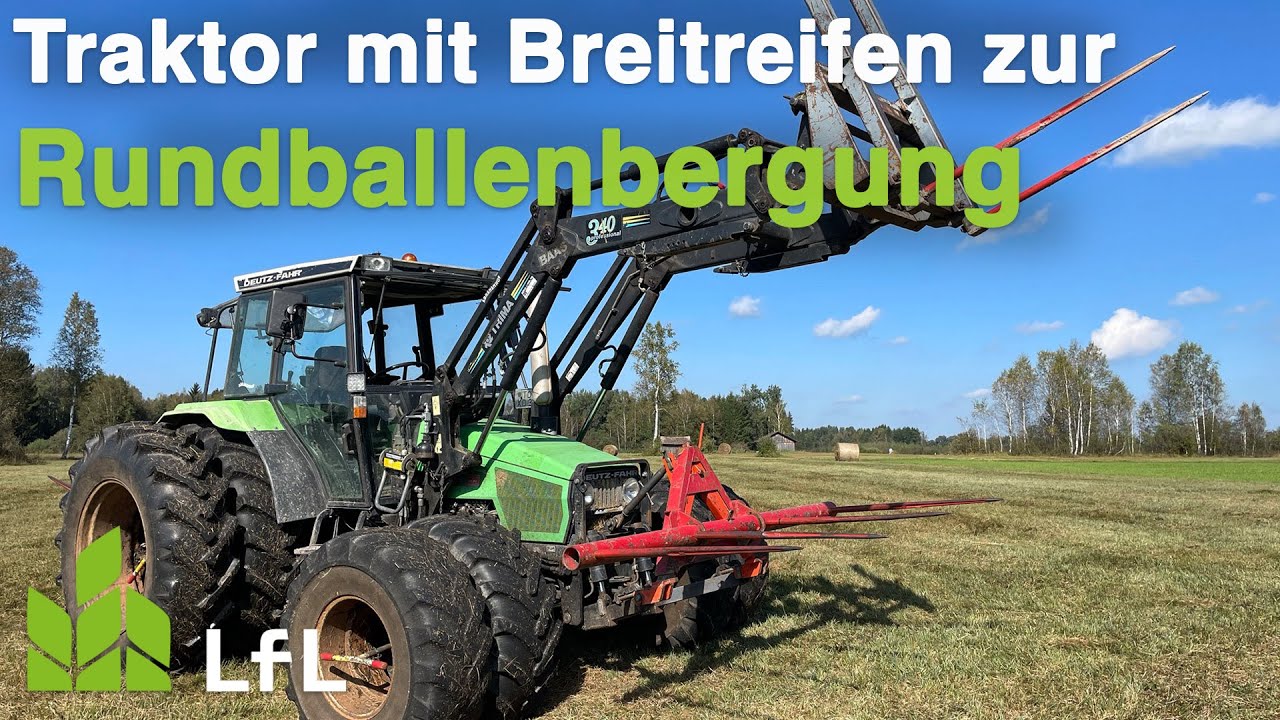 Traktor mit Zwillingsbereifung und drei Ballengabeln zur Rundballenbergung