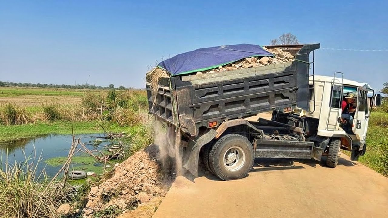 Dumping soil on a concrete road to clear a pond