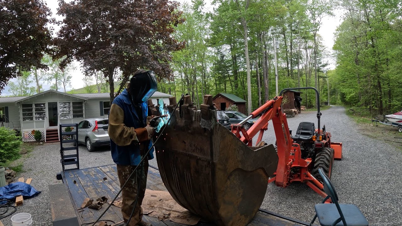 Repairing giant cracks in an excavator bucket then digging out a massive pine