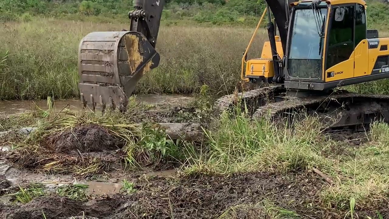 ESCAVADEIRA HIDRÁULICA VOLVO 140DLM LIMPANDO CANAL DE DRENO NO BANHADO USANDO ESTIVAS