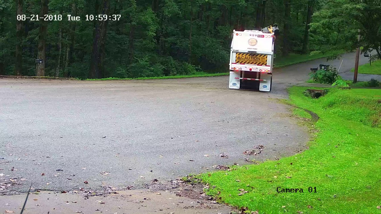Garbage truck driving in the grass/mud.
