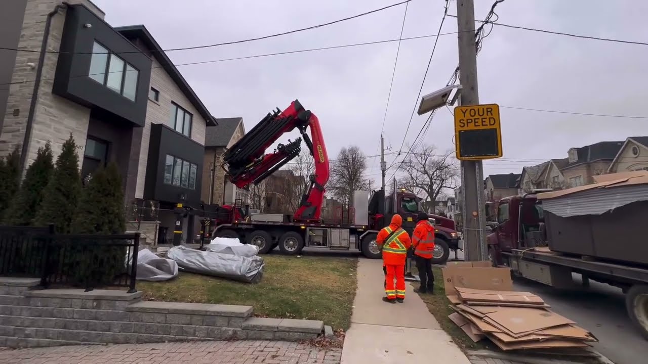 Palfinger PK 200002 knuckle crane lifting swim spa over house in Toronto